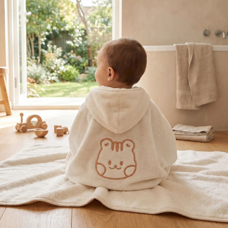 Cape de bain bebe. Bebe est au chaud dans son cape de bain .